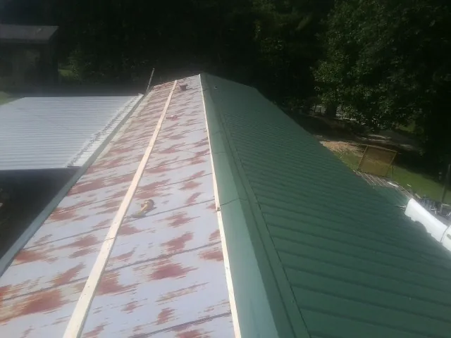 Old rusted panels beside newly installed green metal roofing — Wind Damage Roof Repair by Roofing Brothers in Unionville